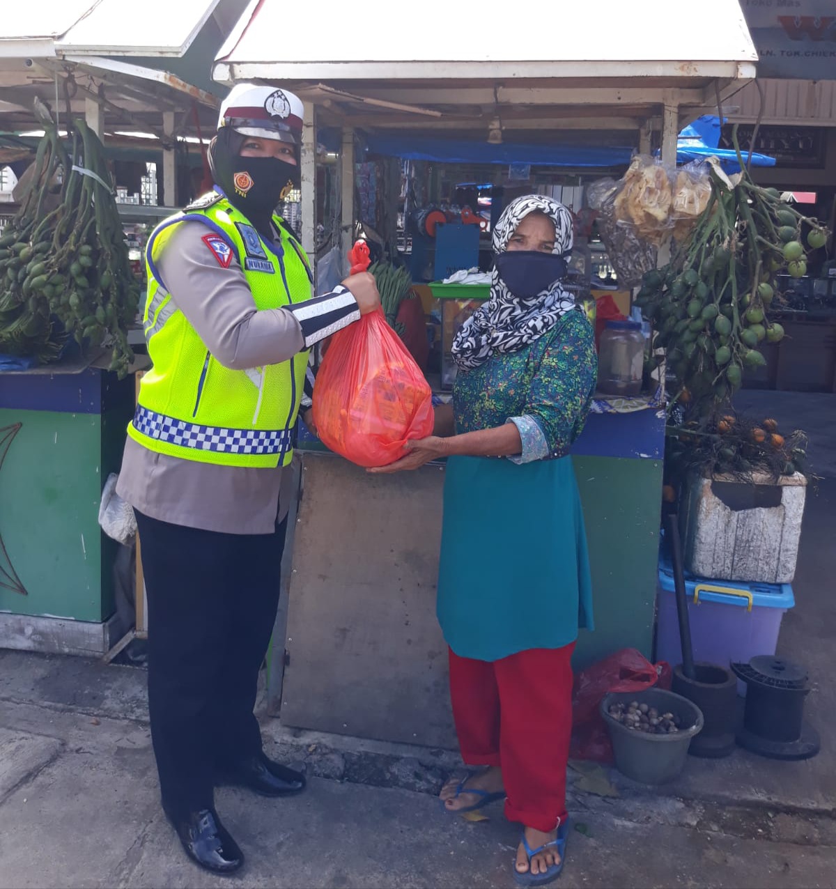 Personel Ditlantas Polda Aceh, menyalurkan sembako kepada penjual sirih dan tukang sol sepatu, di Simpang Ketapang, Banda Aceh. Foto: Humas Ditlantas Polda Aceh